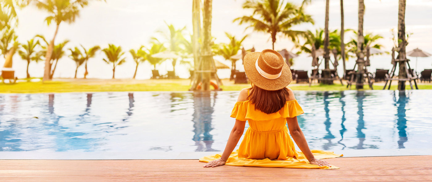 Woman in yellow dress sitting on the edge of a pool