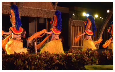 Image of four women in colorful attire, dancing at an evening Luau.