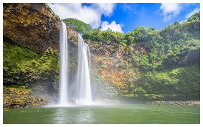 View of the Wailua Falls pouring of of a cliff into a lake.