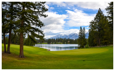 A golf course lake with trees and mountains.