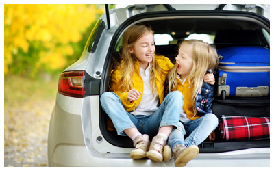 Image of two young girls laughing while sitting in the back of a car