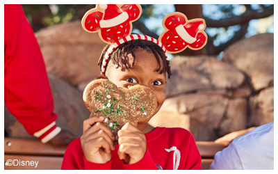 Child holding up Mickey Mouse cookie.